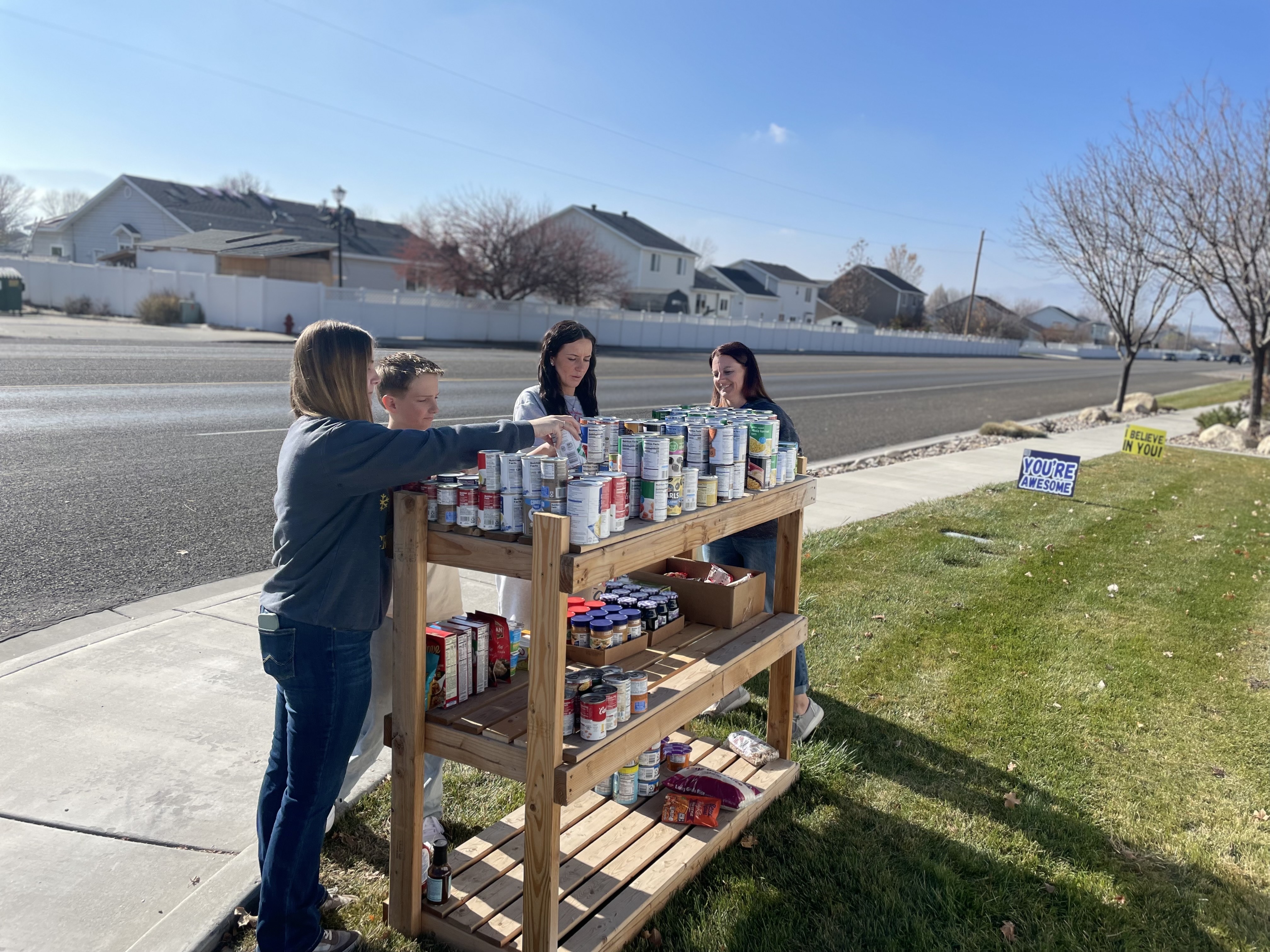 From left, Paige Spaulding, James Avery, Emory Spaulding and Natalie Spaulding place items on a makeshift food pantry in Lehi on Nov. 22.