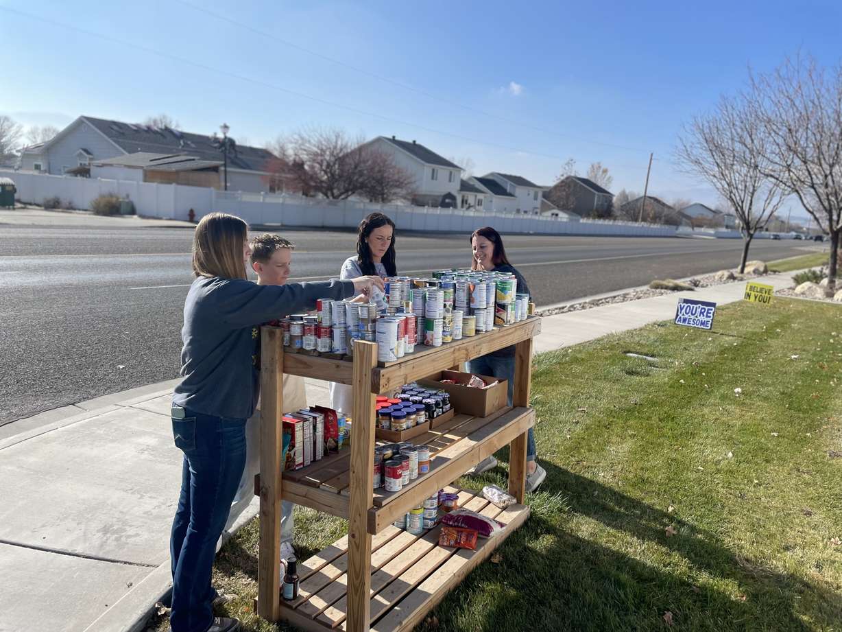 From left, Paige Spaulding, James Avery, Emory Spaulding and Natalie Spaulding place items on a makeshift food pantry in Lehi on Nov. 22.