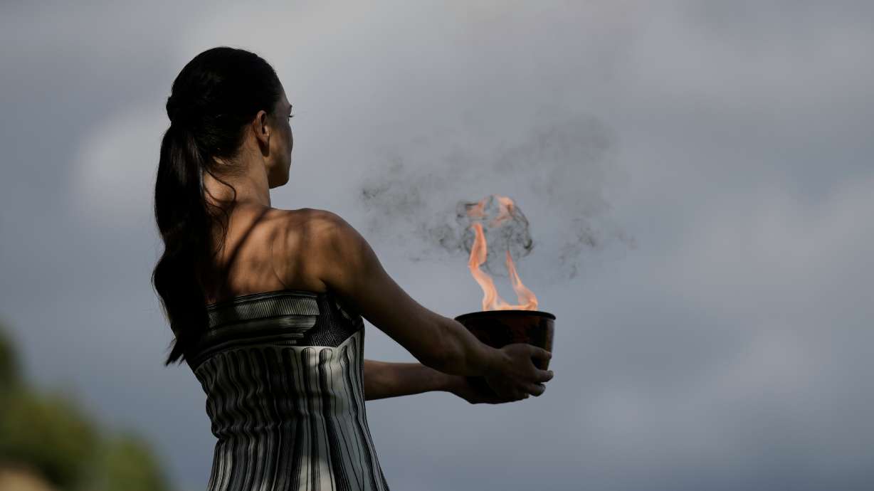 Actress Mary Mina, playing the high priestess holds a pot with the flame during a rehearsal ahead of the flame lighting for the Milan Cortina 2026 Winter Olympics, at the Ancient Olympia site, Greece, Monday, Nov. 24, 2025.
