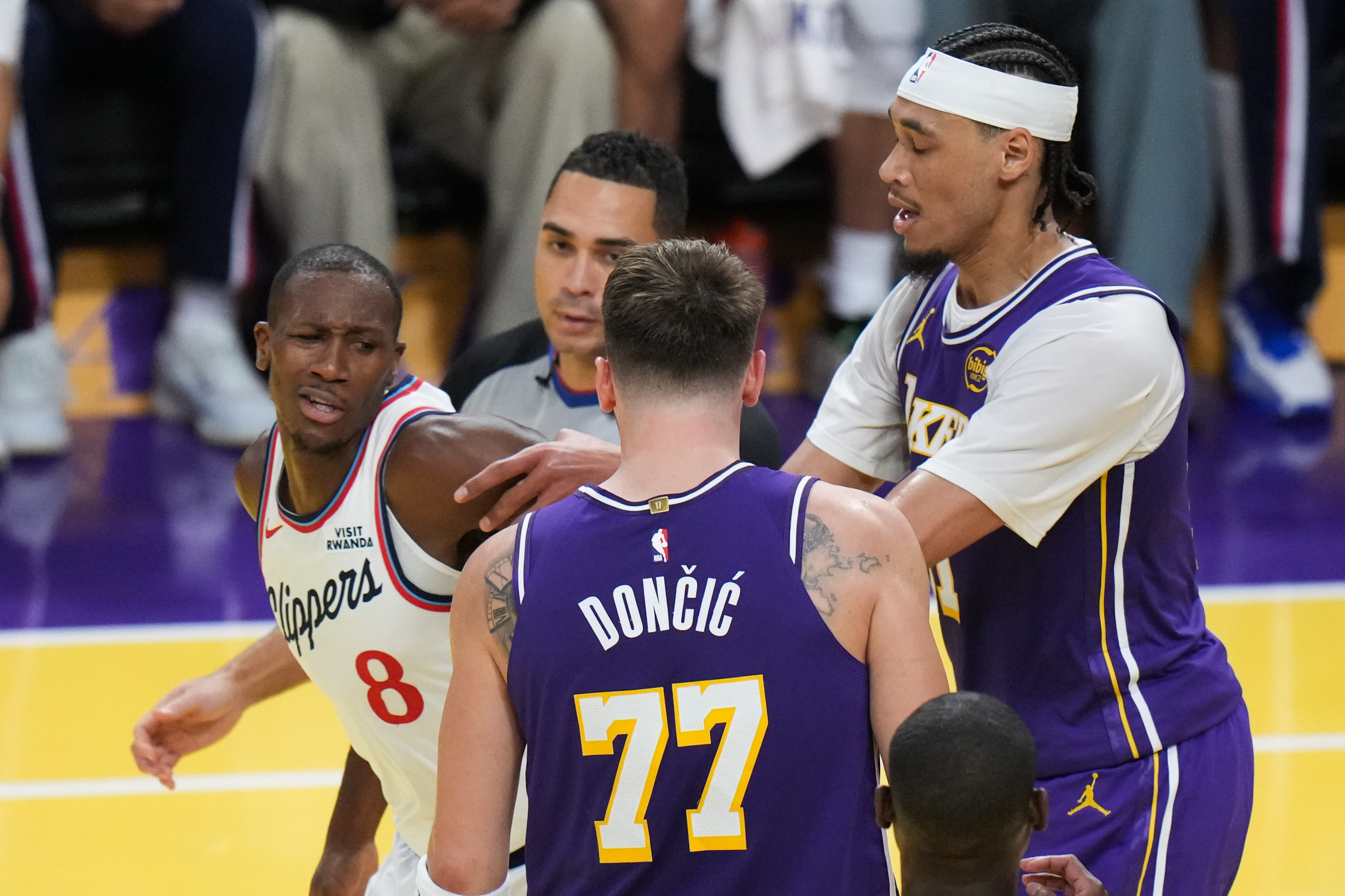 Los Angeles Clippers guard Kris Dunn (8) is pushed by Los Angeles Lakers center Jaxson Hayes (11) after Dunn shoved the ball into Luka Doncic's chest during the second half of an NBA Cup basketball game Tuesday, Nov. 25, 2025, in Los Angeles. 