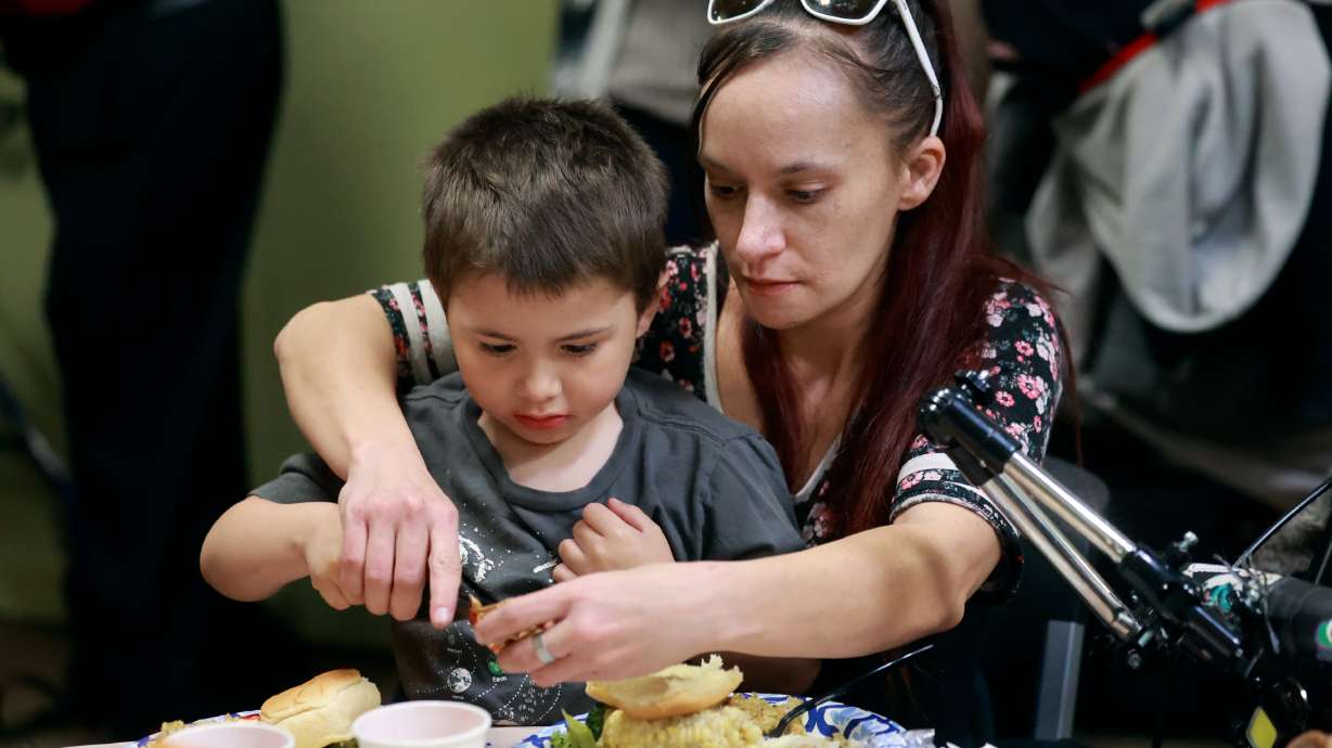 Grayson Smith and his mother Destiny Smith butter a roll during the annual Thanksgiving banquet at the Rescue Mission in Salt Lake City on Wednesday.