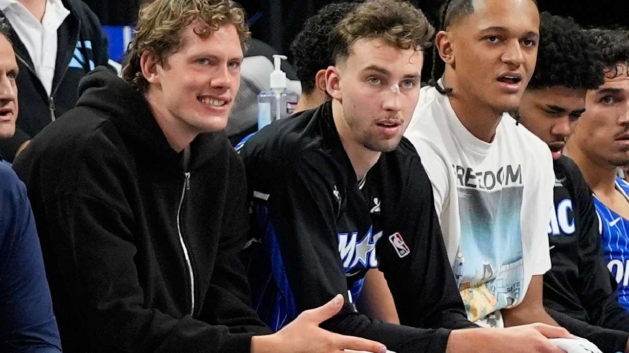 **HOLD FOR STORY BY ROB MADDIE**Orlando Magic players and brothers Moritz Wagner, left, and Franz Wagner, center, watch the first half of an NBA basketball game with teammate Paolo Banchero against the Golden State Warriors, Tuesday, Nov. 18, 2025, in Orlando, Fla.