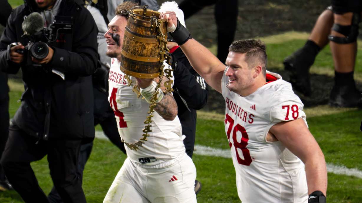Indiana linebacker Aiden Fisher (4) and offensive lineman Pat Coogan (78) celebrate with the Old Oaken Bucket trophy after an NCAA college football game against Purdue, Friday, Nov. 28, 2025, in West Lafayette, Ind.