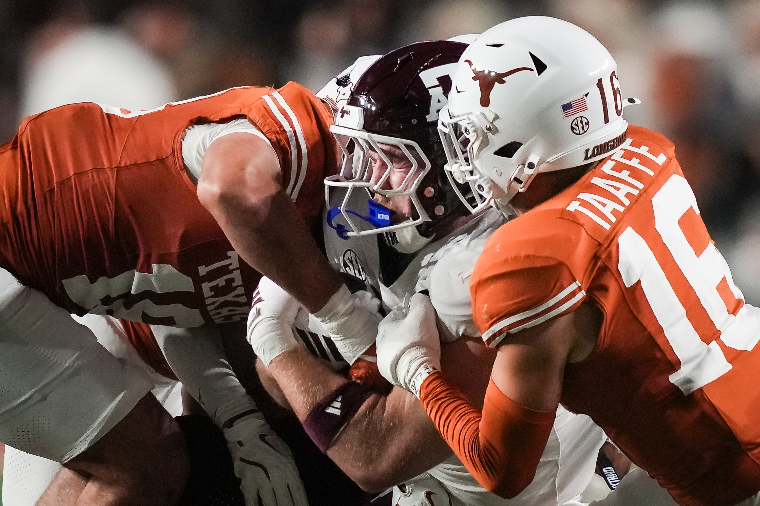 Texas defensive back Warren Roberson (24) and linebacker Liona Lefau (18) bring down Texas A&M tight end Theo Melin Öhrström (17) during the second quarter of an NCAA college football game against Texas A&M in Austin, Texas, Friday, Nov. 28, 2025. 