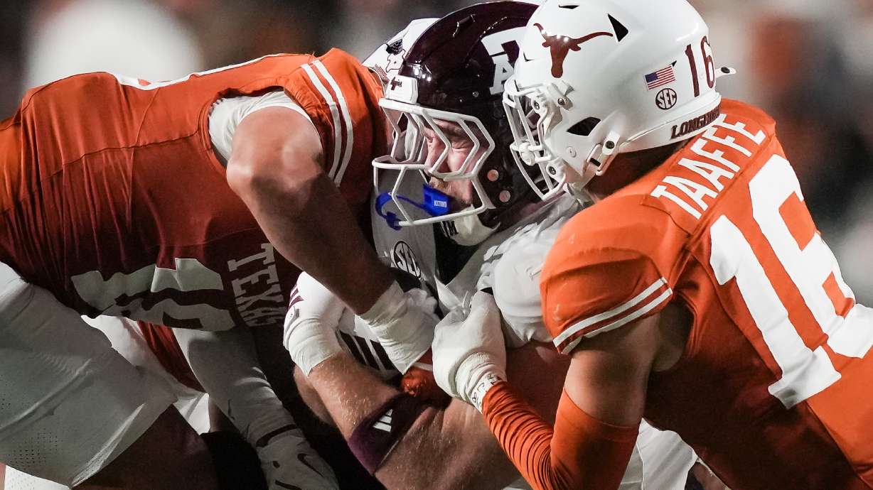 Texas defensive back Warren Roberson (24) and linebacker Liona Lefau (18) bring down Texas A&M tight end Theo Melin Öhrström (17) during the second quarter of an NCAA college football game against Texas A&M in Austin, Texas, Friday, Nov. 28, 2025.