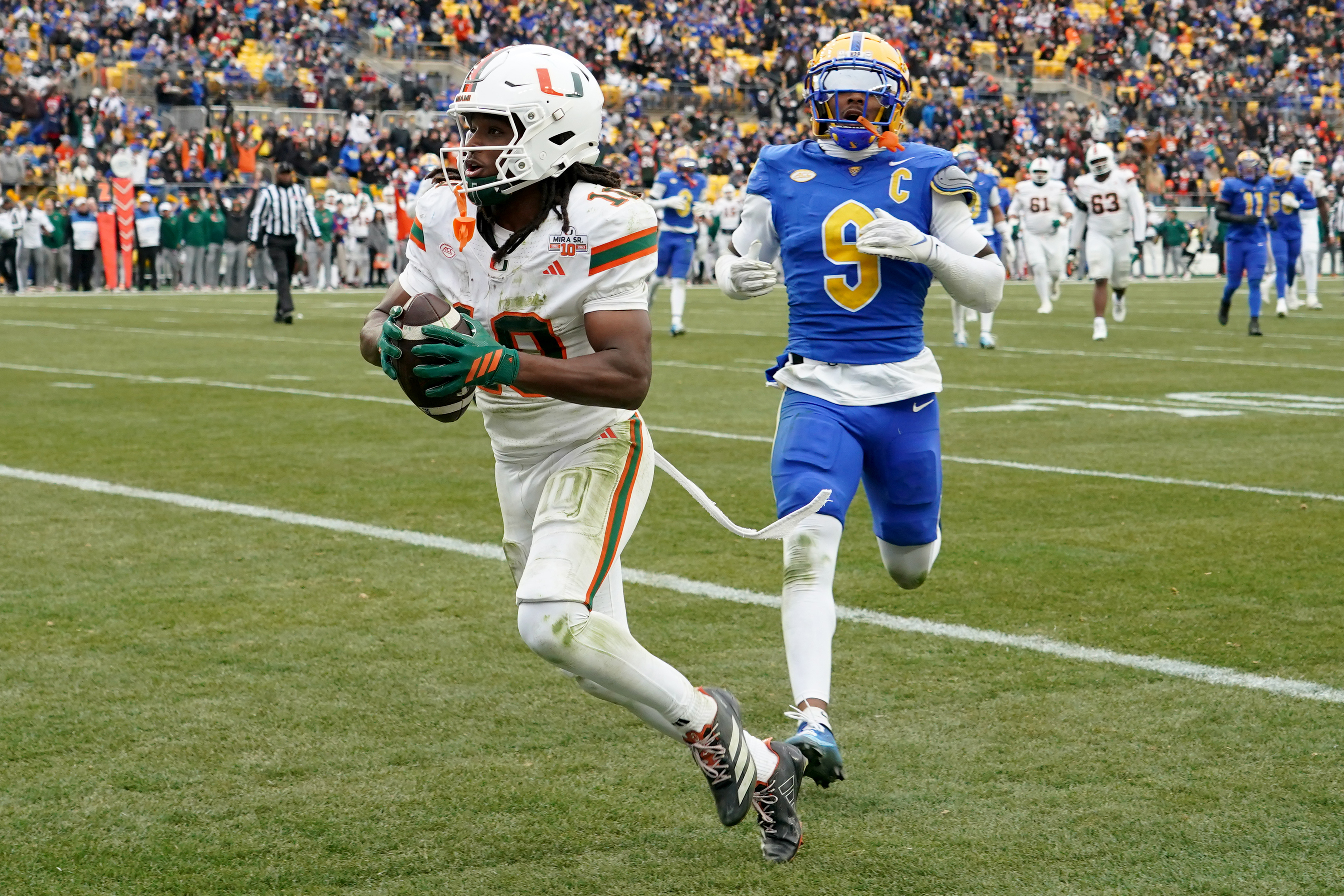 Miami wide receiver Malachi Toney (10) scores in front of Pittsburgh linebacker Kyle Louis (9) during the first half of an NCAA college football game, Saturday, Nov. 29, 2025, in Pittsburgh. 