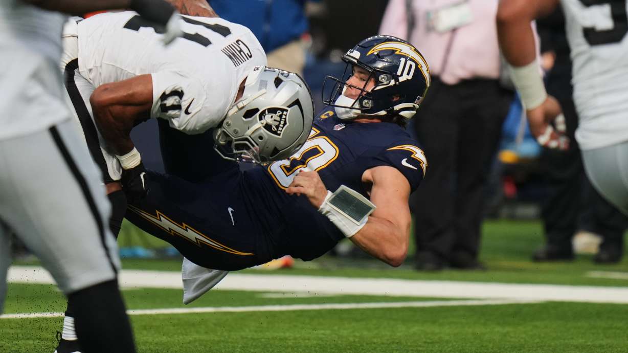 Las Vegas Raiders safety Jeremy Chinn (11) tackles Los Angeles Chargers quarterback Justin Herbert (10) during the first half of an NFL football game, Sunday, Nov. 30, 2025, in Inglewood, Calif.