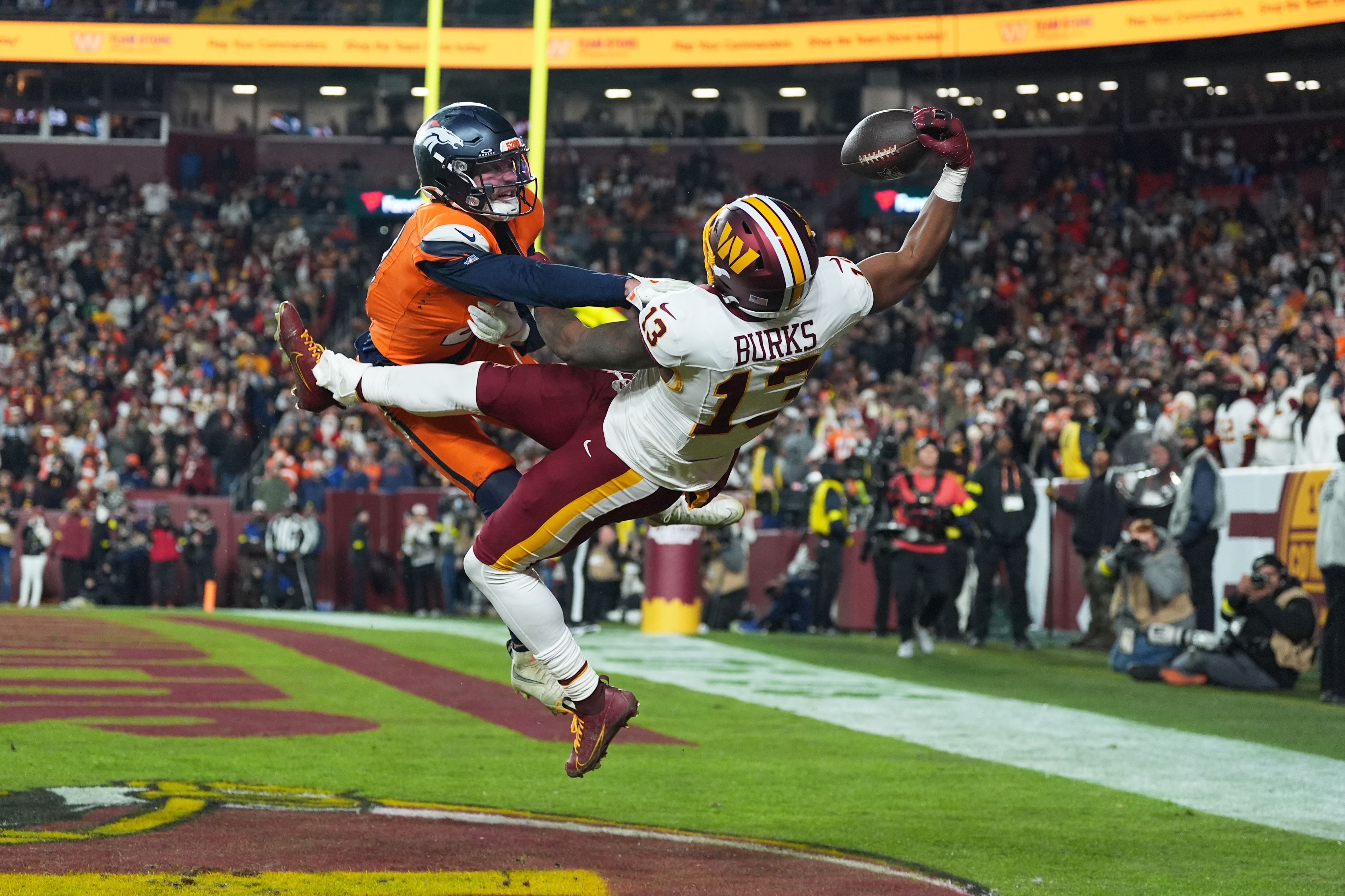 Washington Commanders wide receiver Treylon Burks (13) catches a touchdown pass as Denver Broncos cornerback Riley Moss, left, defends during the second half of an NFL football game Sunday, Nov. 30, 2025, in Landover, Md.
