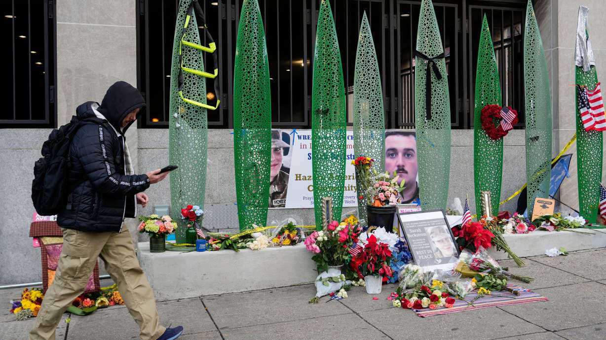 A person walks past a makeshift memorial for U.S. Army Spc. Sarah Beckstrom and U.S. Air Force Staff Sgt. Andrew Wolfe outside of Farragut West Station, near the site where the two National Guard members were shot, Monday, in Washington.