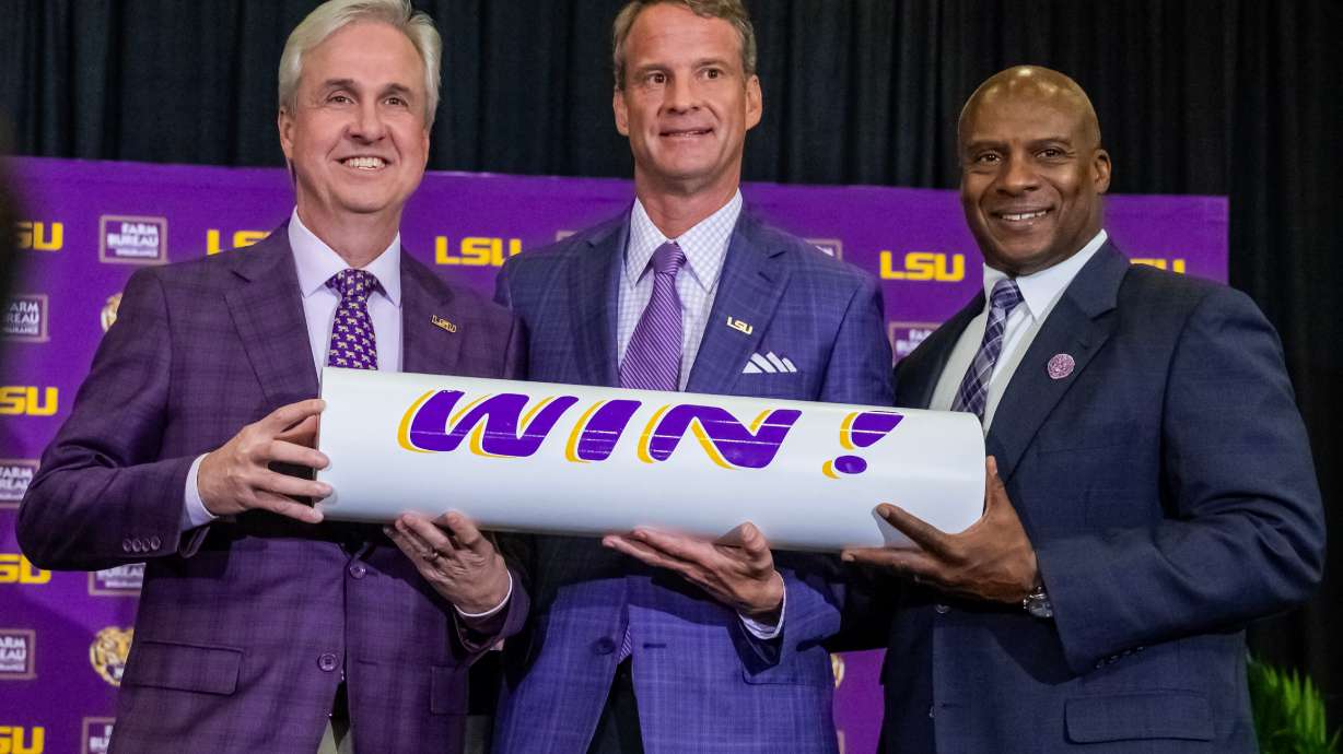 LSU president Wade Rousse, left, and athletic director Verge Ausberry, right, pose with new head football coach Lane Kiffin after after an introductory news conference, Monday, Dec. 1, 2025, in Baton Rouge, La.