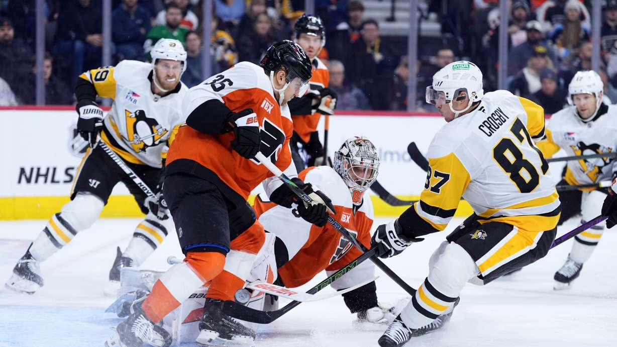 Pittsburgh Penguins' Sidney Crosby (87) scores a goal against Philadelphia Flyers' Dan Vladar (80) and Emil Andrae (36) during the first period of an NHL hockey game Monday, Dec. 1, 2025, in Philadelphia.