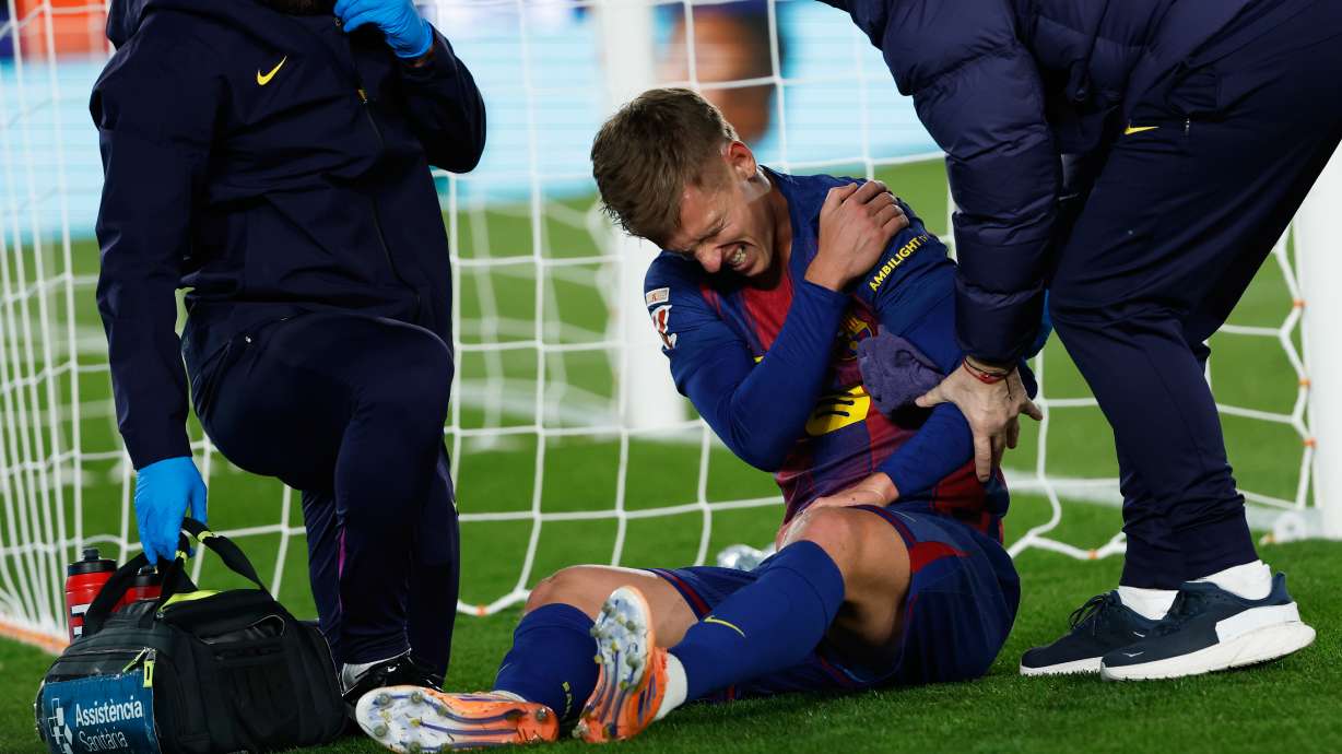 Barcelona's Dani Olmo reacts in pain in his arm after scoring his side's second goal during a Spanish La Liga soccer match between Barcelona and Atletico de Madrid, in Barcelona, Spain, Tuesday, Dec.2, 2025.