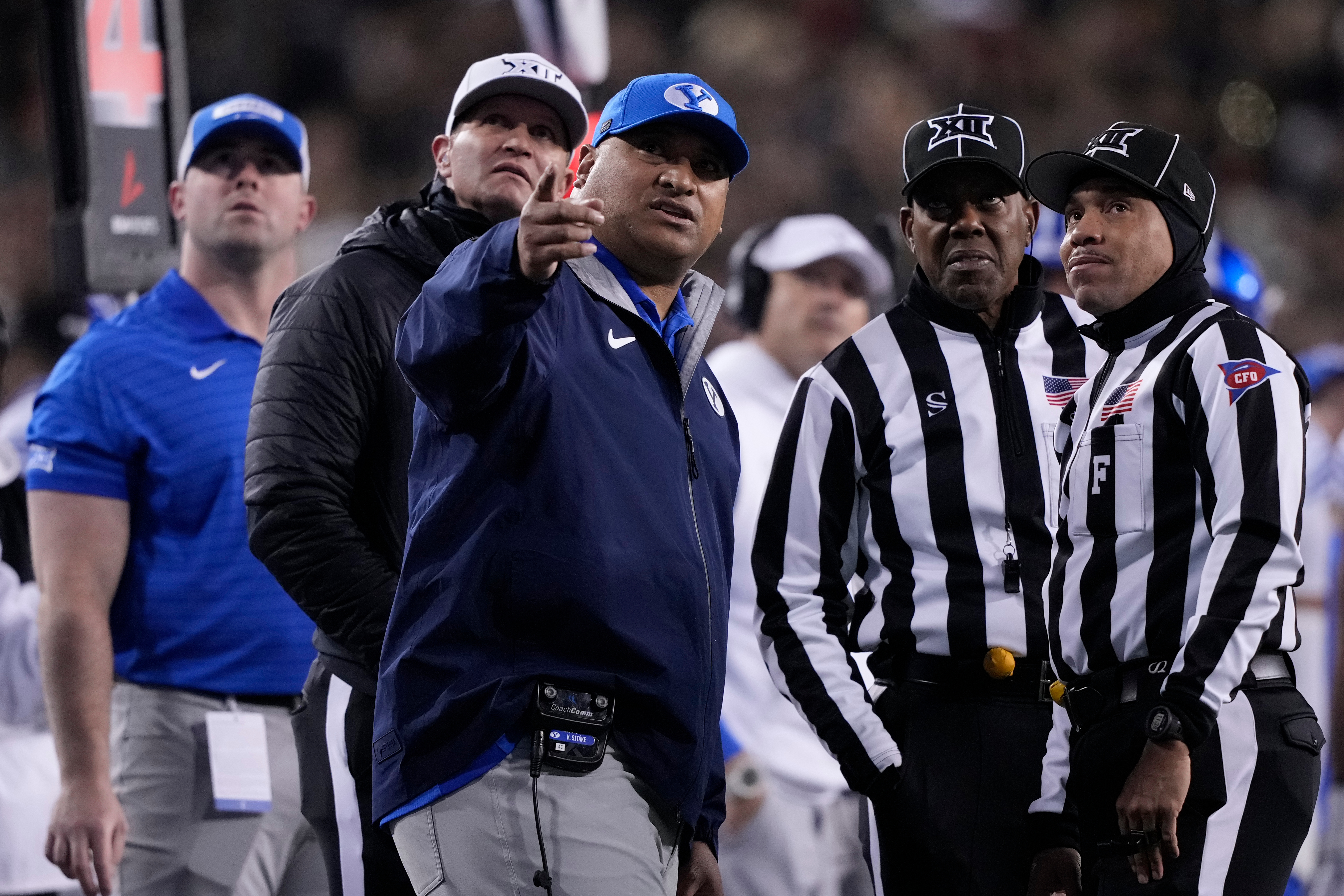 BYU head coach Kalani Sitake, center, looks to a replay with officials during the first half of an NCAA college football game against Cincinnati, Saturday, Nov. 22, 2025, in Cincinnati.