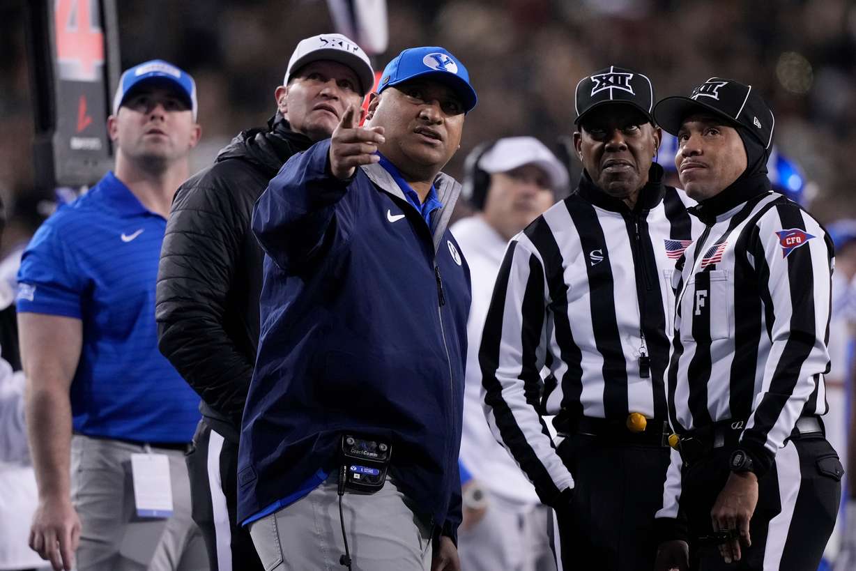 BYU head coach Kalani Sitake, center, looks to a replay with officials during the first half of an NCAA college football game against Cincinnati, Saturday, Nov. 22, 2025, in Cincinnati.