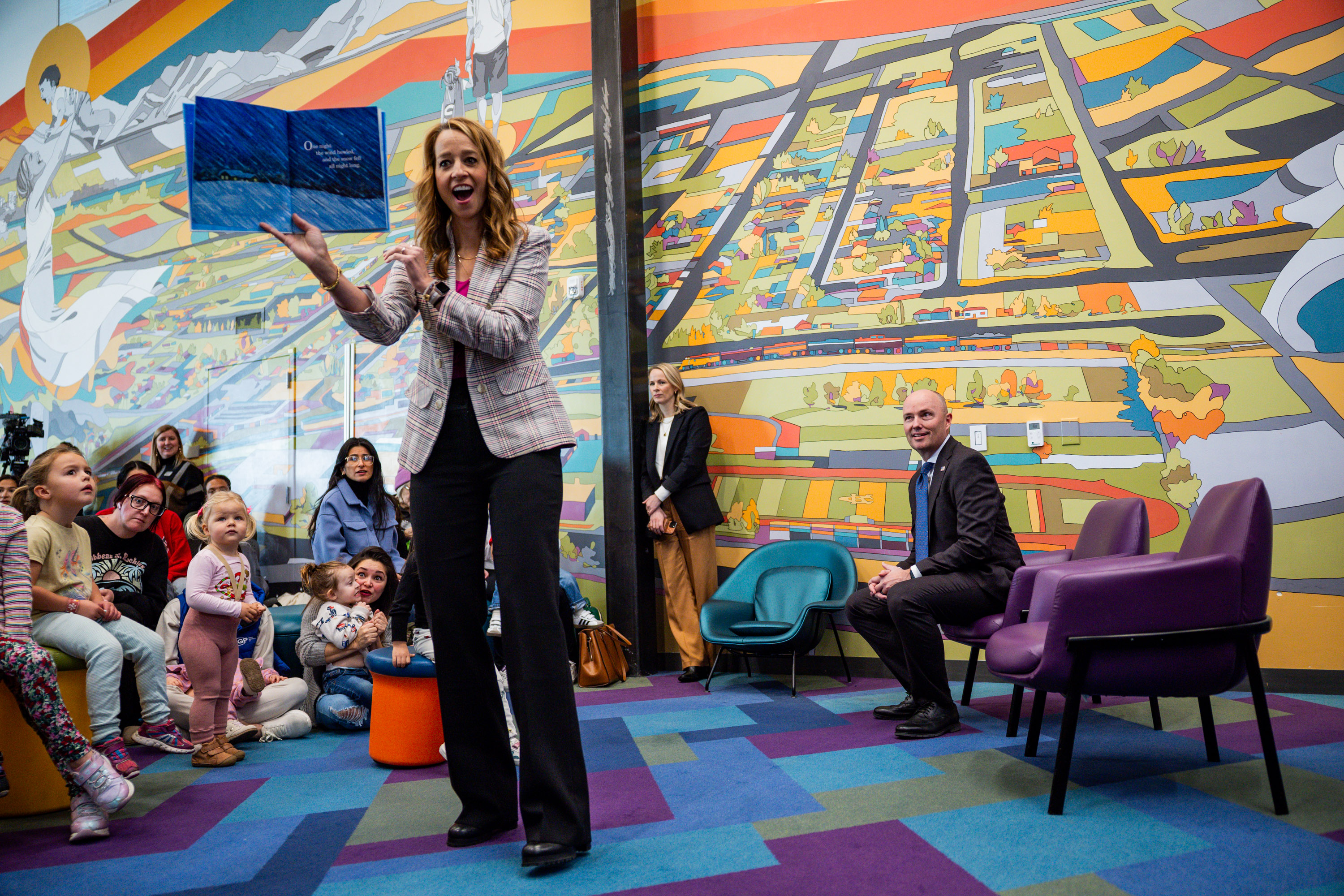 Gov. Spencer Cox, right, smiles as first lady Abby Cox reads to children at Kearns Library in Kearns on Wednesday.
