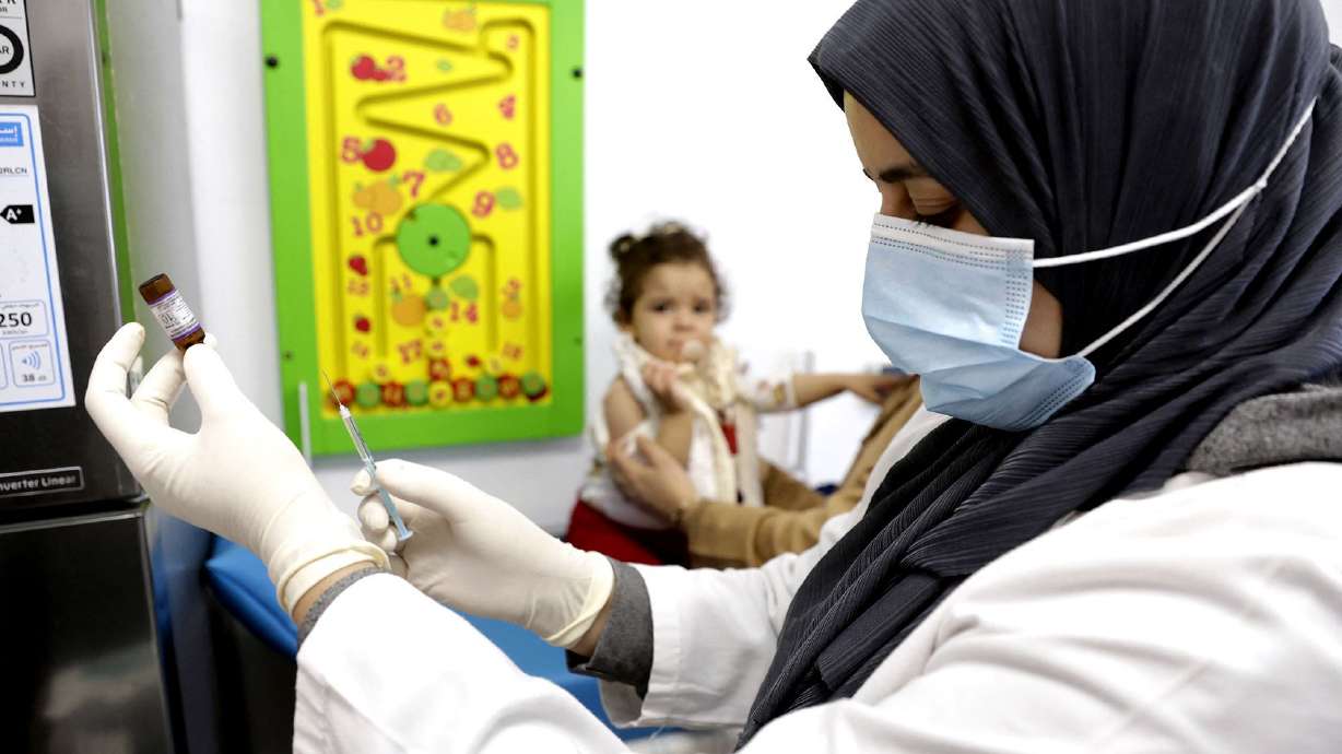 A child waits as a nurse prepares a dose of measles vaccine at a hospital in the Moroccan coastal city of Temara in February 2025. Measles and meningitis infections killed at least 100,000 children around the world in 2023, according to WHO data.