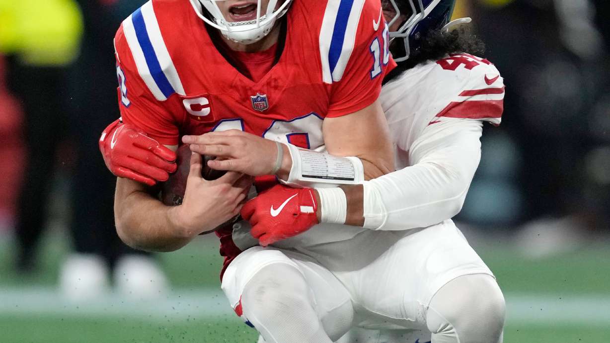 New England Patriots quarterback Drake Maye, front, is sacked by New York Giants linebacker Zaire Barnes, back, during the second half of an NFL football game Monday, Dec. 1, 2025, in Foxborough, Mass.