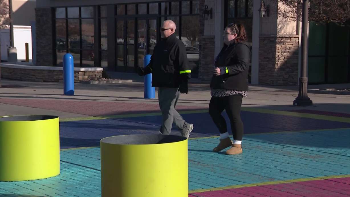 Two demonstrators walking across a crosswalk with reflective wristbands, showing how this could save lives, Thursday. Utah law enforcement is urging people to take action to prevent pedestrian deaths in the dark.