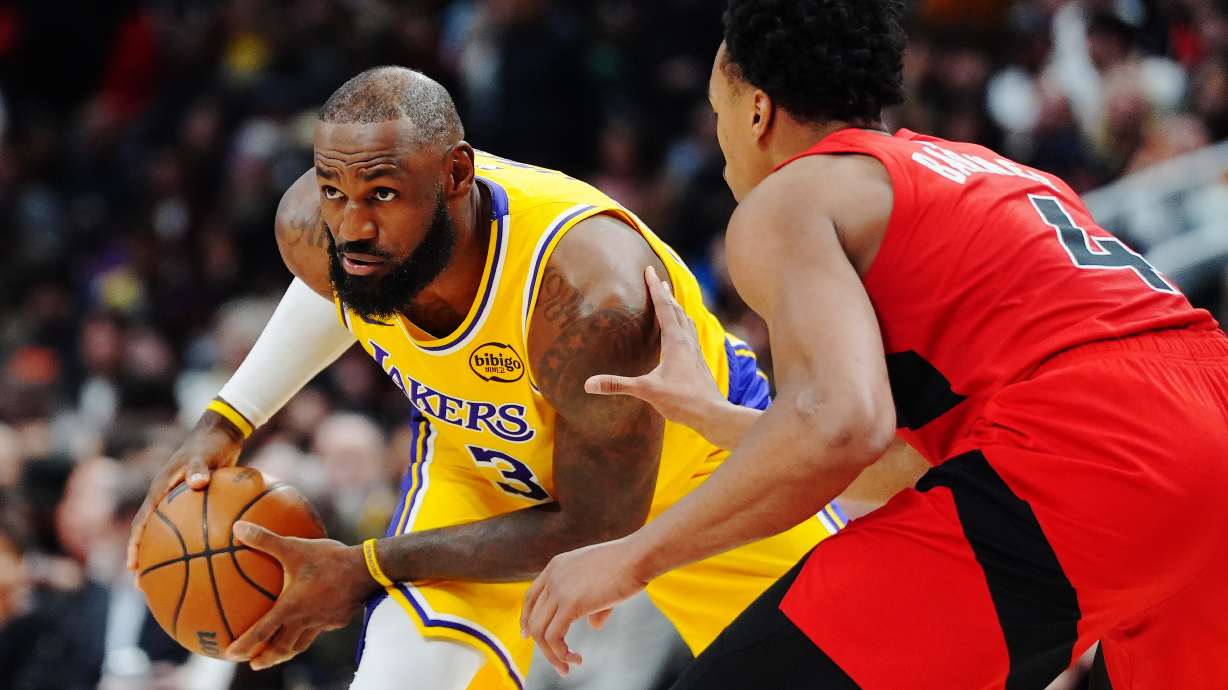 Los Angeles Lakers' LeBron James, left, is guarded by Toronto Raptors' Scottie Barnes (4) during second-half NBA basketball game action in Toronto, Thursday, Dec. 4, 2025.