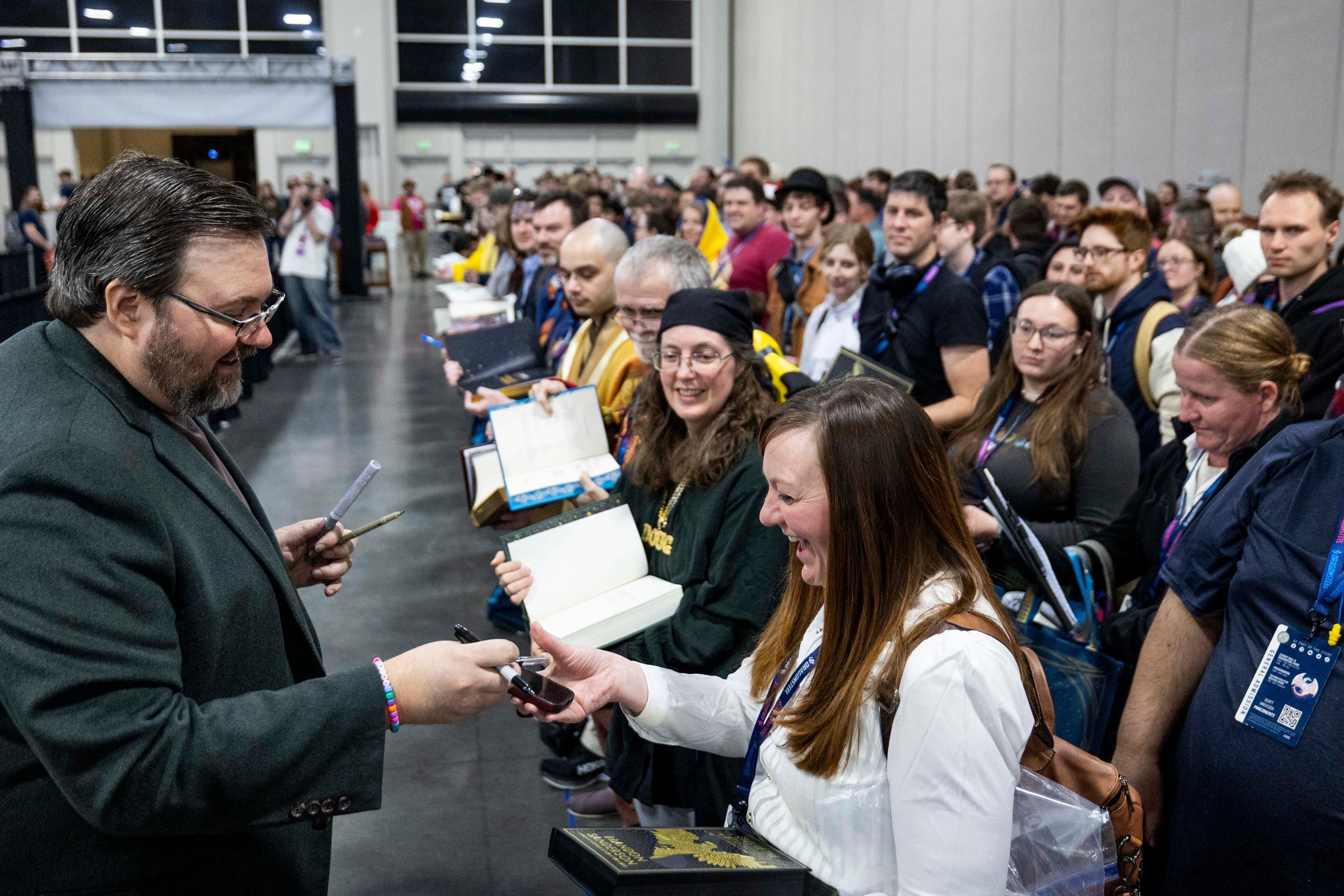 Brandon Sanderson smiles as he interacts with fans during a lightning signing session during Dragonsteel Nexus at the Salt Palace Convention Center in Salt Lake City on Thursday. Sanderson announced a new Cosmere novel as part of the event.