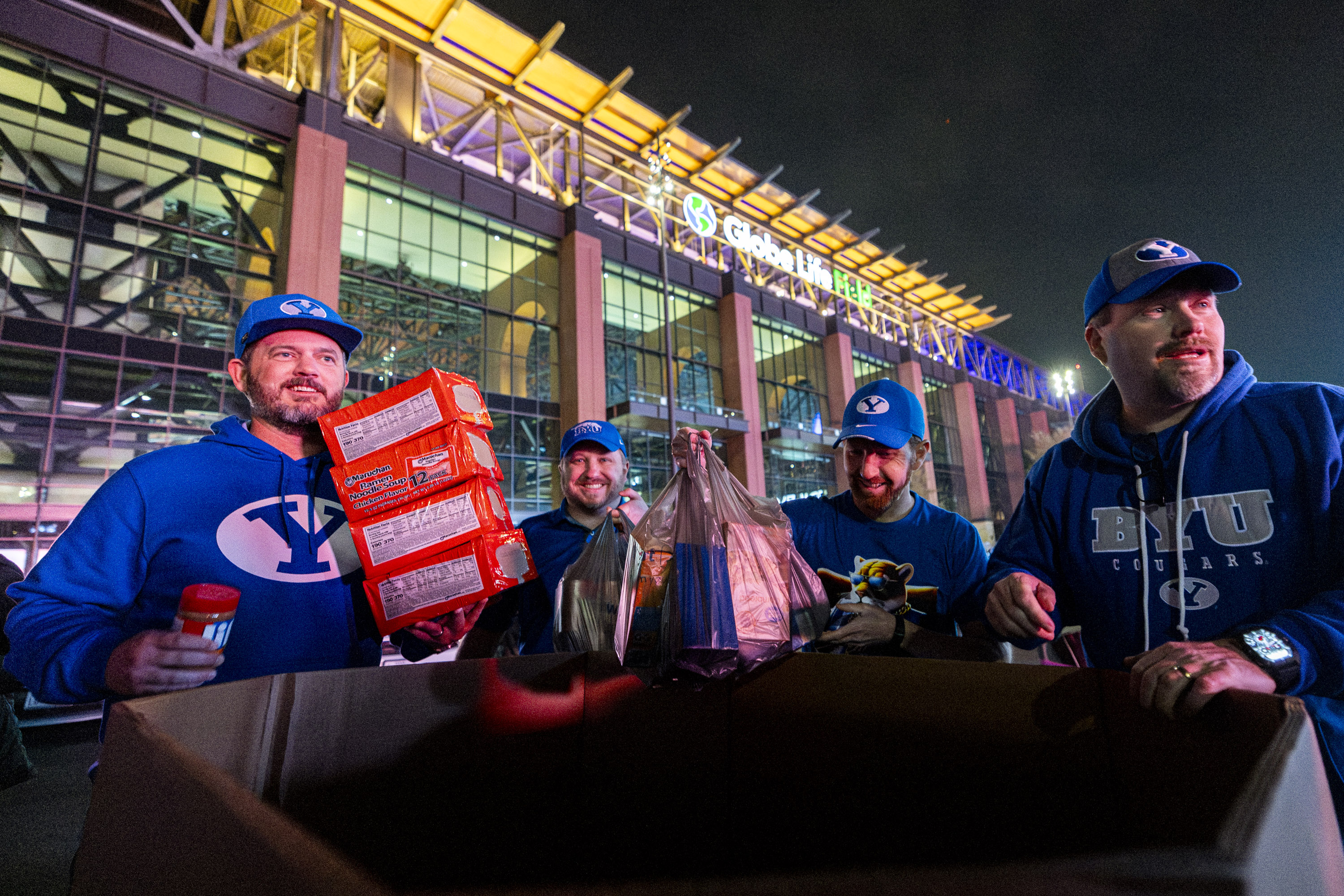 From left, Tyler Lund, Andrew Lund, Cameron Lund, and Ryan Lund, all relatives living in Utah County, donate food as part of a food drive with Arlington Charities during pregame festivities for BYU fans held the day before the Big 12 championship game at Globe Life Field in Arlington, Texas, on Friday, Dec. 5, 2025.