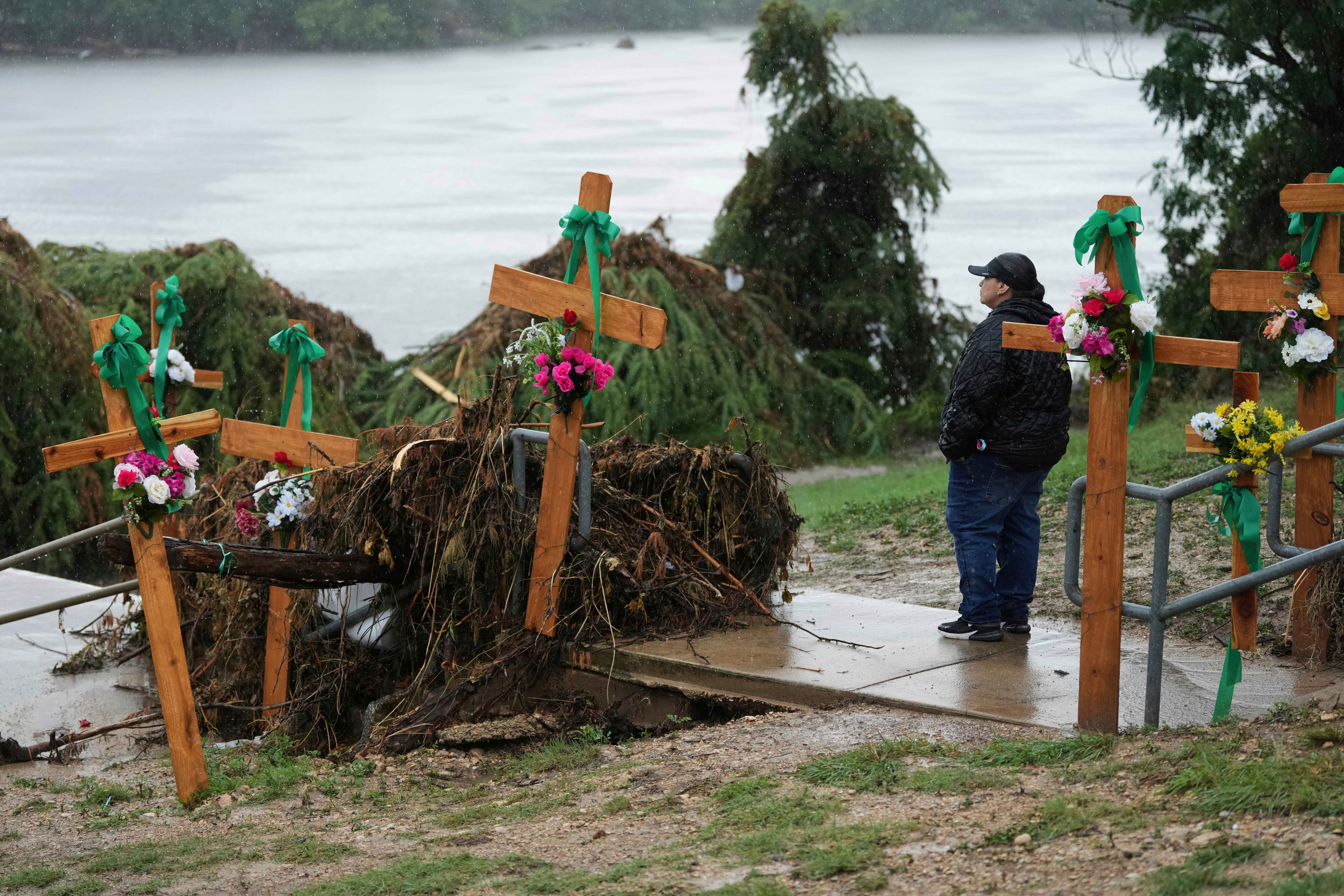 Rain falls as Irene Valdez visits a makeshift memorial for flood victims along the Guadalupe River, July 13 in Kerrville, Texas.