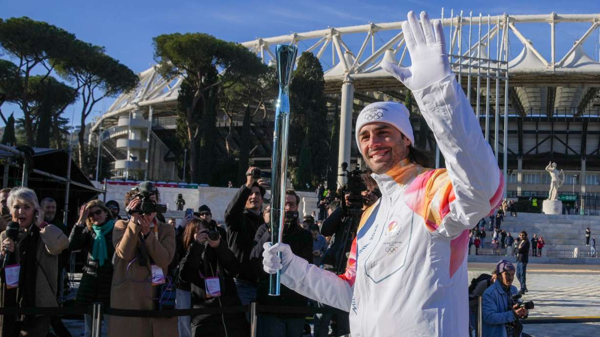 Italian swimmer Gregorio Paltrinieri carries the 2026 Milan Cortina Winter Olympics torch in Rome as it begins its journey through Italy, Saturday, Dec. 6, 2025, a journey that will conclude in Milan in February 2026.