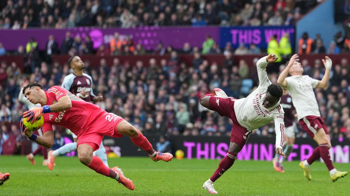 Aston Villa's goalkeeper Emiliano Martinez, left, makes a save ahead of Arsenal's Bukayo Saka during the English Premier League soccer match between Aston Villa and Arsenal in Birmingham, England, Saturday, Dec. 6, 2025.