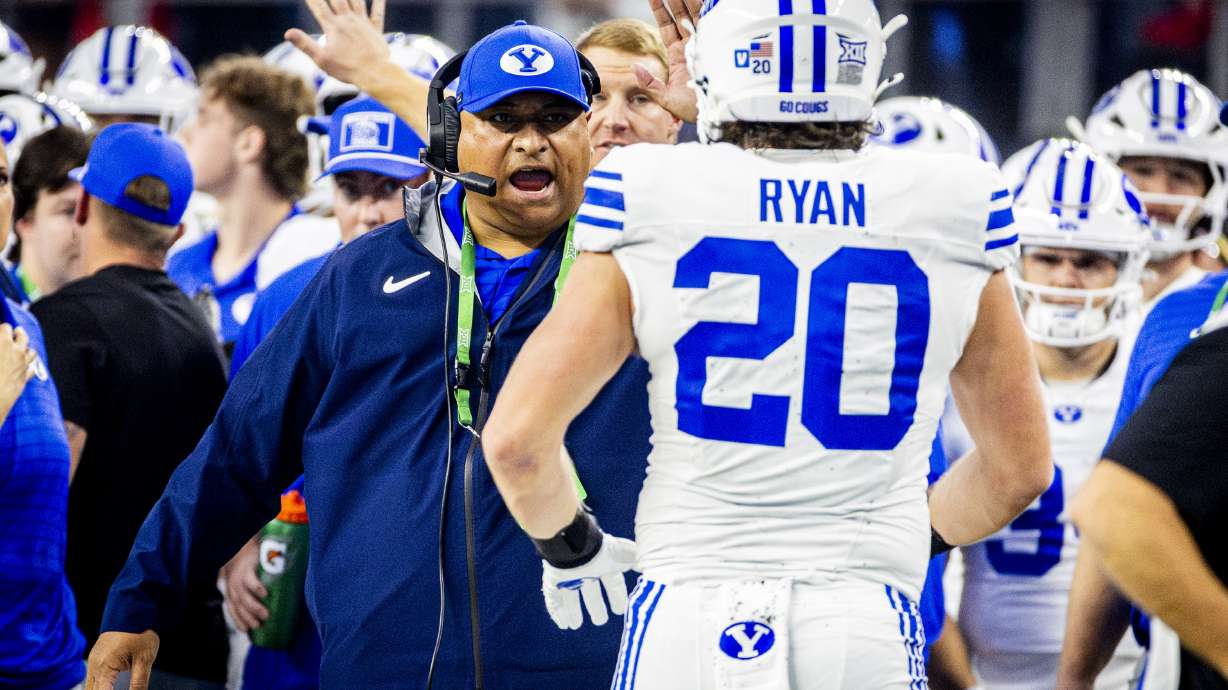 BYU head coach Kalani Sitake high-fives tight end Carsen Ryan (20) after a play during the Big 12 championship game against Texas Tech at AT&T Stadium in Arlington, Texas, on Saturday, Dec. 6, 2025.
