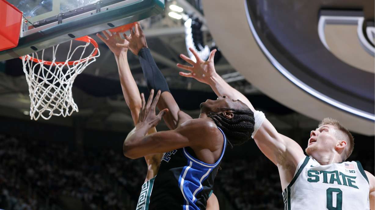 Duke guard Dame Sarr, center, and Michigan State forward Jaxon Kohler (0), right, and forward Jordan Scott, rear, vie for a rebound during the first half of an NCAA college basketball game, Saturday, Dec. 6, 2025, in East Lansing, Mich.