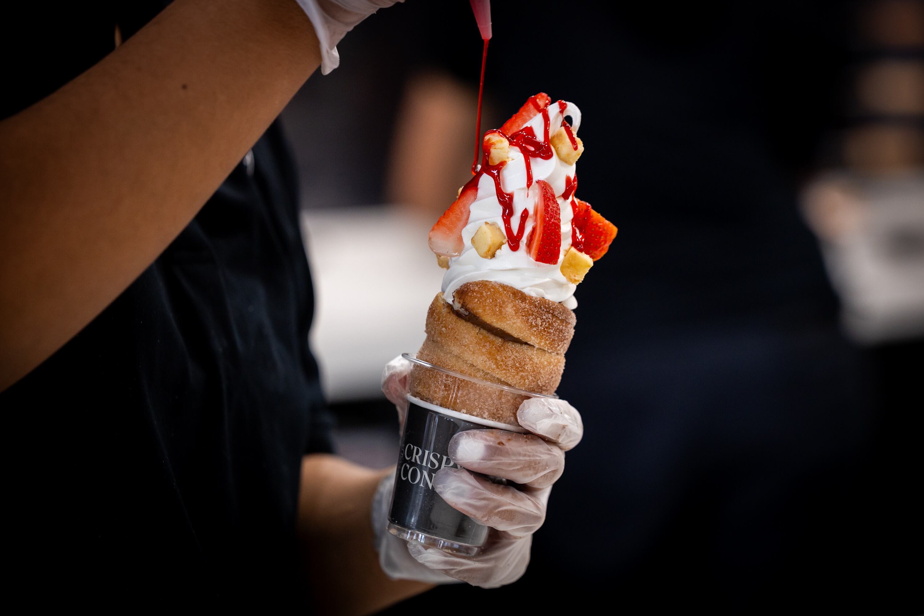 An employee prepares a cone to serve to a customer at the opening of a new Crispy Cones location in Draper on Nov. 21. The cones are loaded up with fruits and other goodies after being made.