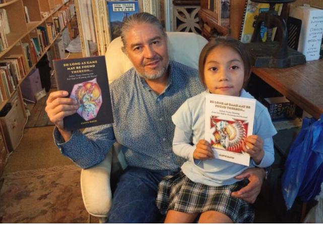 Author Cleve Davis and his daughter Isla Rain, 8, show off a hardback and a paperback copy of his new book “So Long As Game May Be Found Thereon…” The cover art was done by Burdett Bird Osborne, a self-taught Shoshone-Bannock artist.