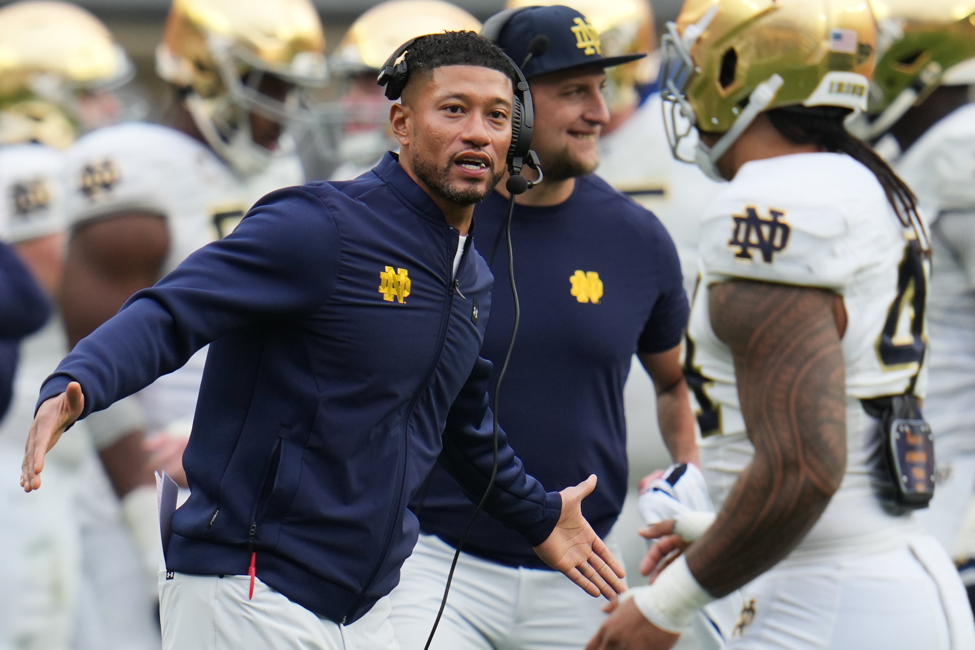 Notre Dame head coach Marcus Freeman, left, greets players as they return to the sideline during the second half of an NCAA college football game against Pittsburgh in Pittsburgh, Saturday, Nov. 15, 2025.
