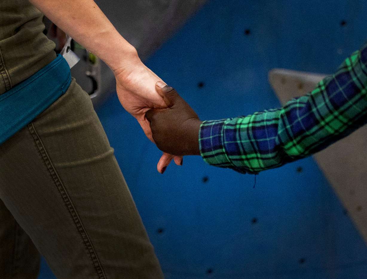 Amidu Zakariy takes Catholic Community Services volunteer Quinn Hennessy’s hand during an outing at Momentum Climbing Gym in Millcreek on Nov. 12.