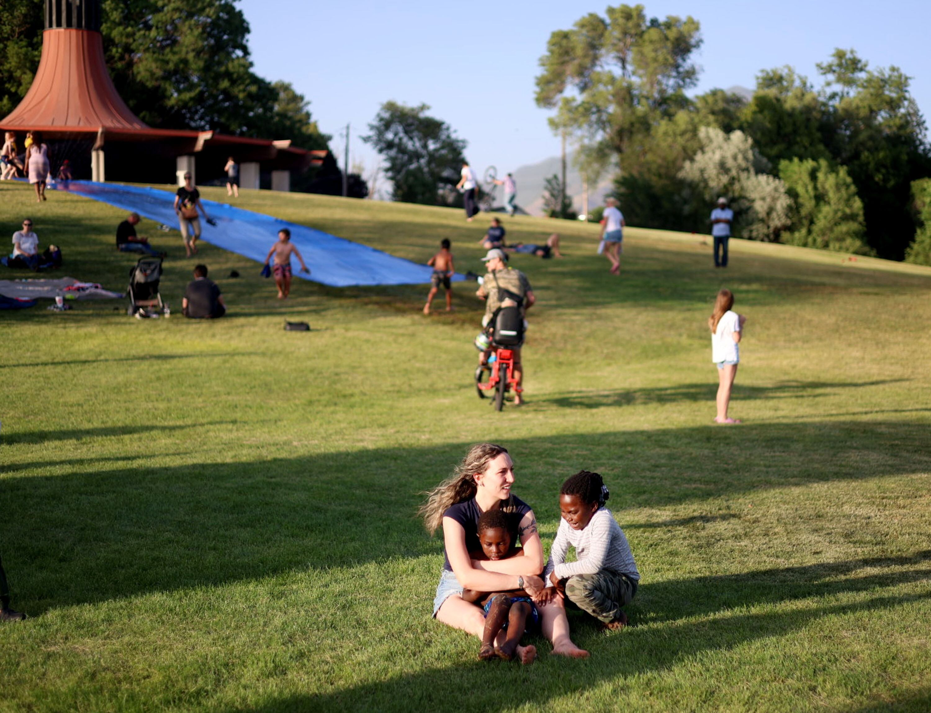 Quinn Hennessy sits with Amidu and Jamila Zakaria at the 21st annual Utah Refugee Day celebration at the Big Cottonwood Regional Park in Millcreek on June 20.