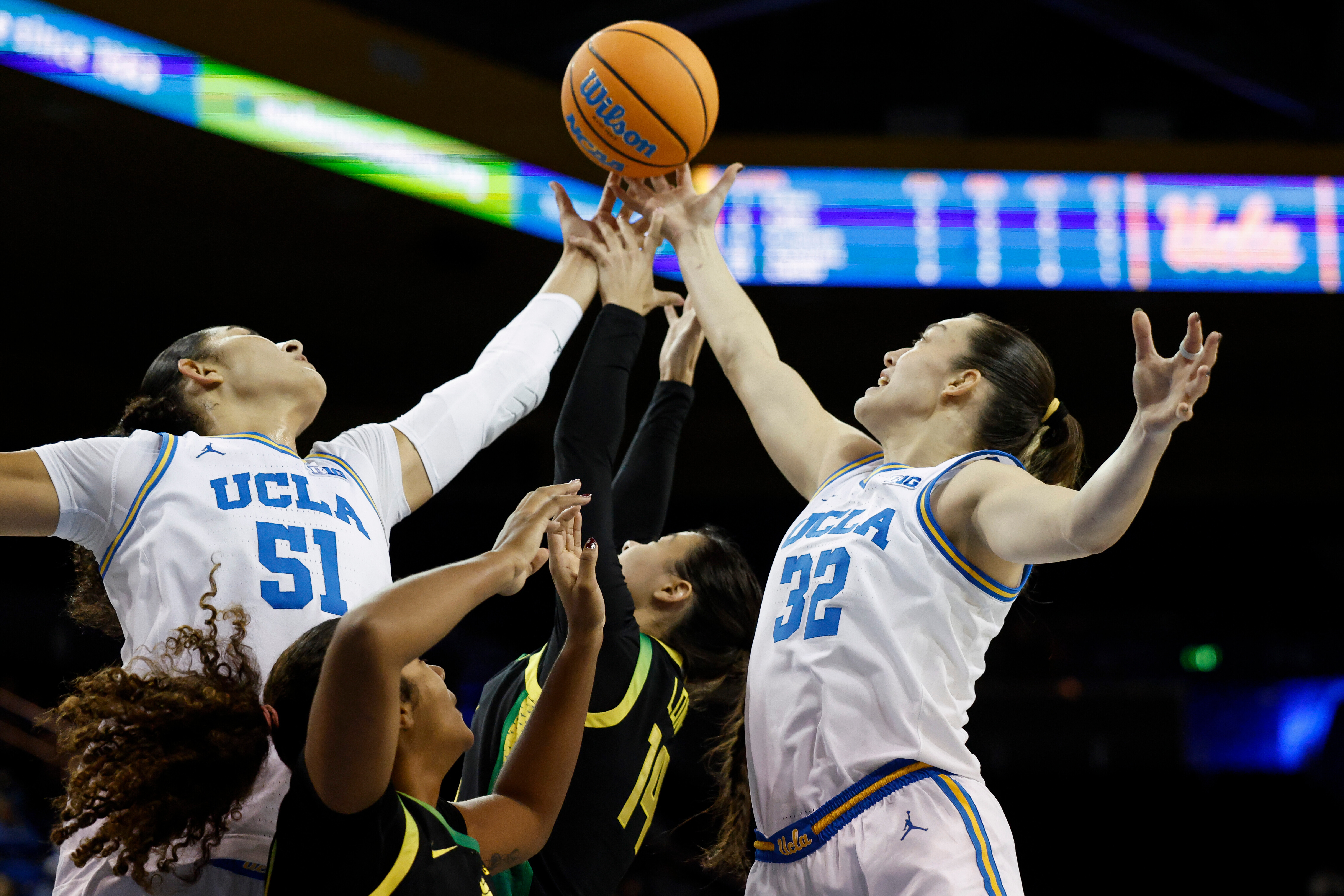 UCLA center Lauren Betts (51), Oregon forward Ehis Etute, second from left, Oregon guard Ari Long (14) and Oregon forward Angela Dugalić (32) reach for the ball during the first half of an NCAA college basketball game Sunday, Dec. 7, 2025, in Los Angeles. 