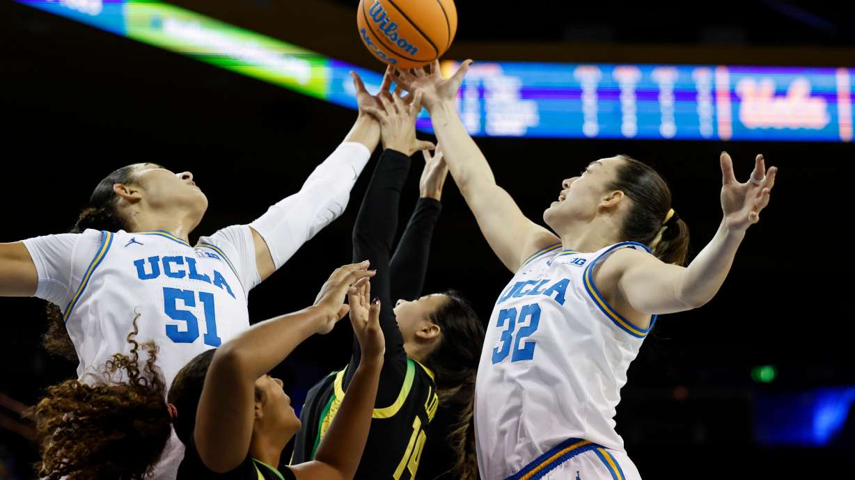 UCLA center Lauren Betts (51), Oregon forward Ehis Etute, second from left, Oregon guard Ari Long (14) and Oregon forward Angela Dugalić (32) reach for the ball during the first half of an NCAA college basketball game Sunday, Dec. 7, 2025, in Los Angeles.