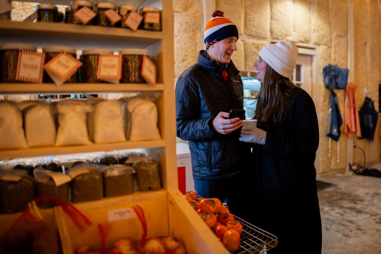 Claire Butz, right, and husband Will Smith, left, from Park City, shop at Ballerina Farm’s winter market before their tree lighting ceremony in Kamas on Friday, Dec. 5, 2025.