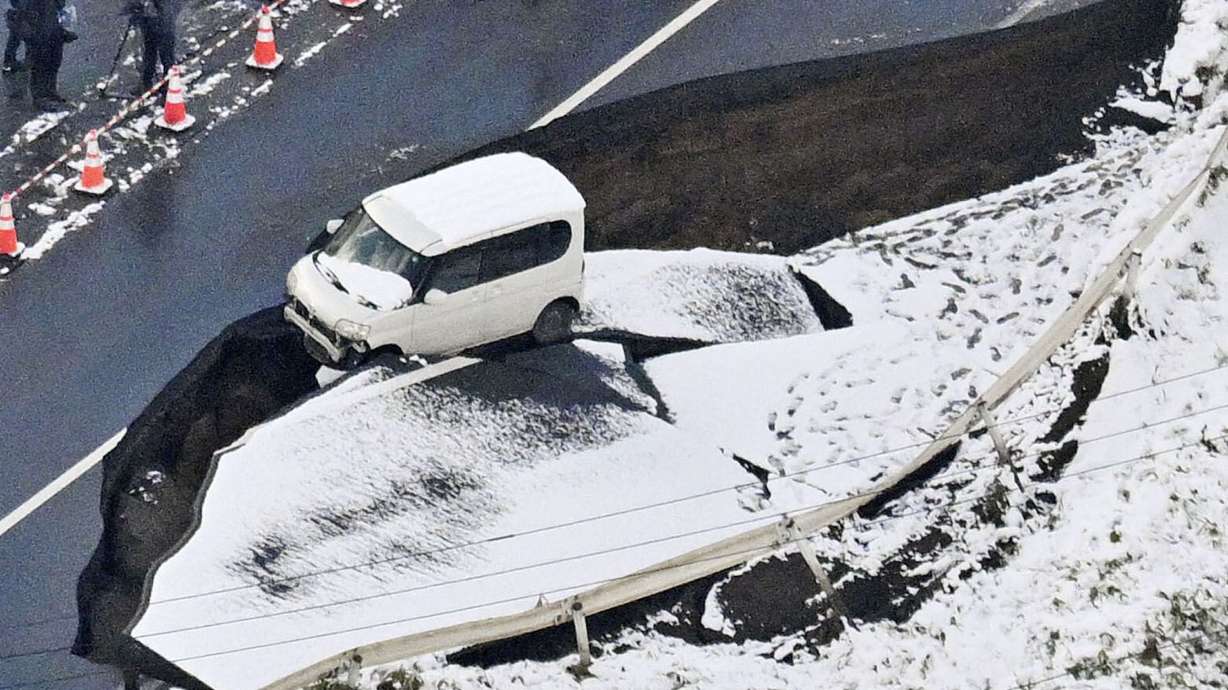 This aerial photo shows a vehicle sitting on a damaged road in Tohoku town, Aomori prefecture, northern Japan Tuesday, following a powerful earthquake on late Monday.