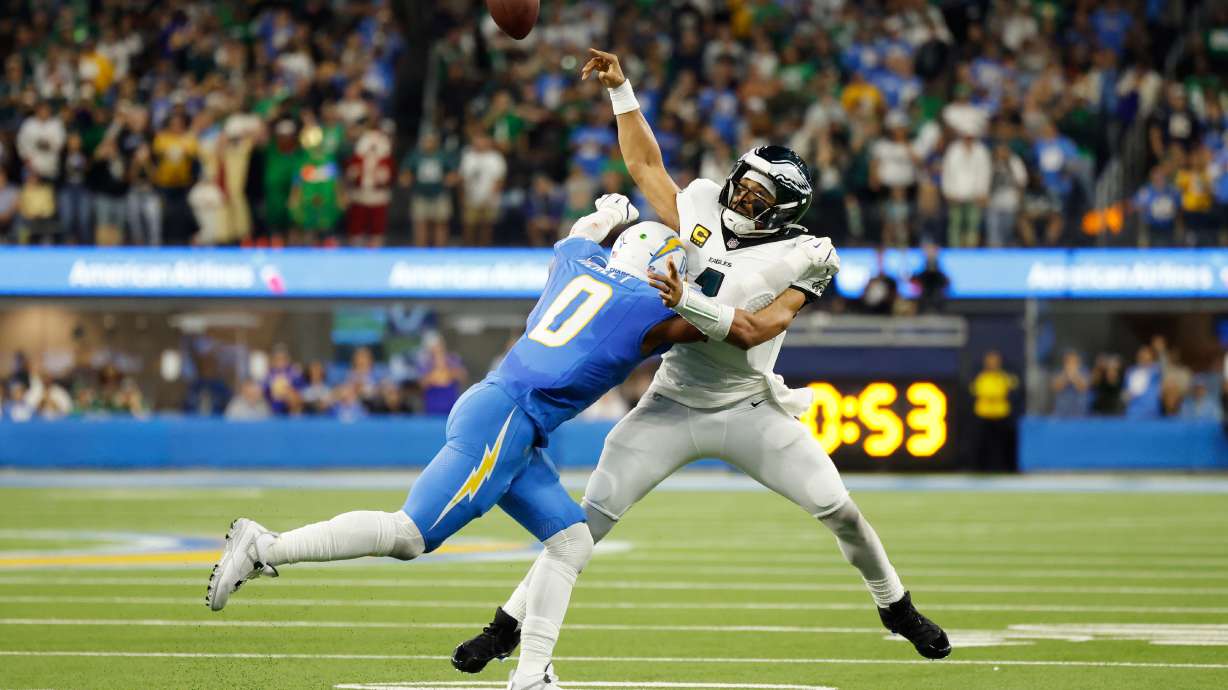 Philadelphia Eagles quarterback Jalen Hurts (1) throws as he is tackled by Los Angeles Chargers linebacker Daiyan Henley (0) during the first half of an NFL football game Monday, Dec. 8, 2025, in Inglewood, Calif.