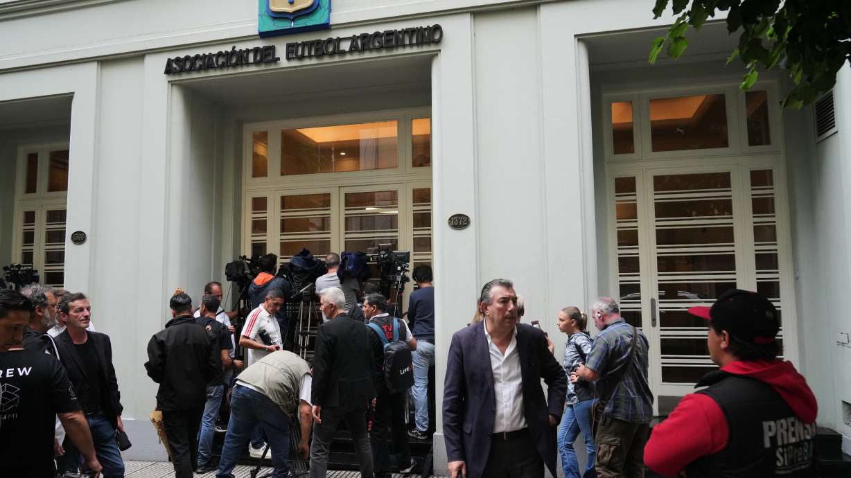 Journalists gather outside the Argentine Soccer Association (AFA) headquarters being raided as part of a judicial investigation into links authorities allege AFA has with a financial services company being investigated for alleged money laundering in Buenos Aires, Argentina, Tuesday, Dec. 9, 2025.