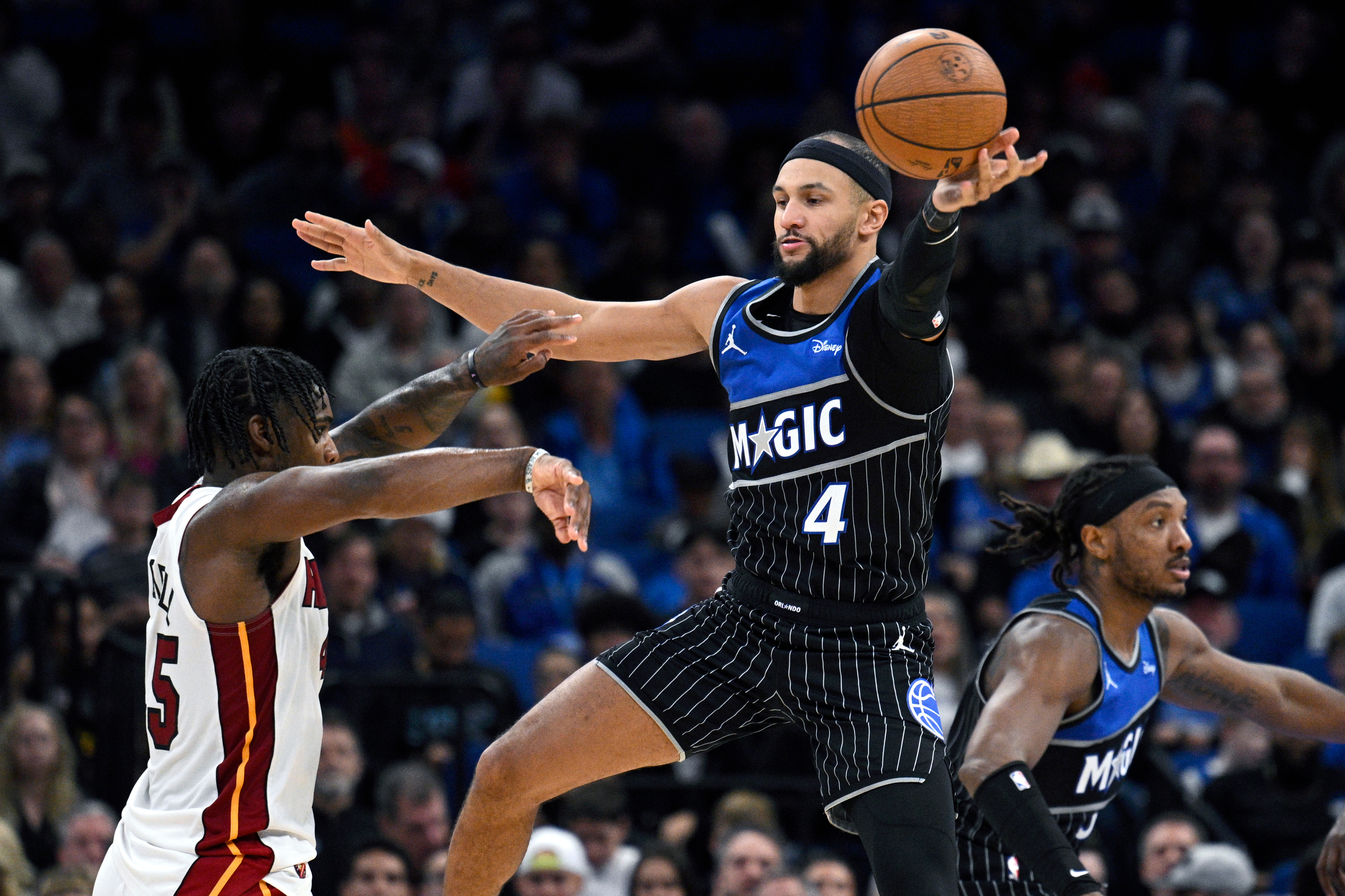 Orlando Magic guard Jalen Suggs (4) deflects a pass by Miami Heat guard Davion Mitchell, left, during the second half of an NBA Cup basketball game, Tuesday, Dec. 9, 2025, in Orlando, Fla. 