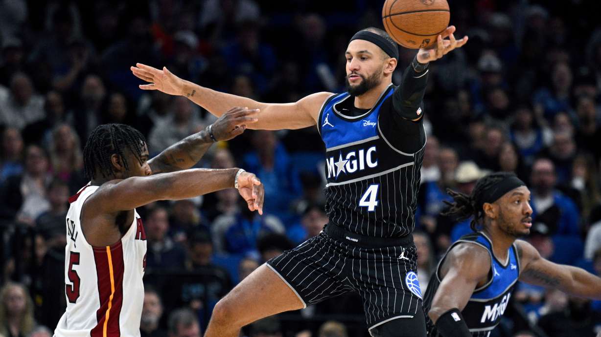 Orlando Magic guard Jalen Suggs (4) deflects a pass by Miami Heat guard Davion Mitchell, left, during the second half of an NBA Cup basketball game, Tuesday, Dec. 9, 2025, in Orlando, Fla.