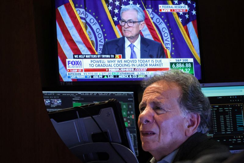 A trader works, as a screen broadcasts a news conference by Federal Reserve Chair Jerome Powell following the Fed rate announcement, on the floor of the New York Stock Exchange in New York City, Wednesday. Stocks closed higher following the announcement of a quarter-percentage point cut.