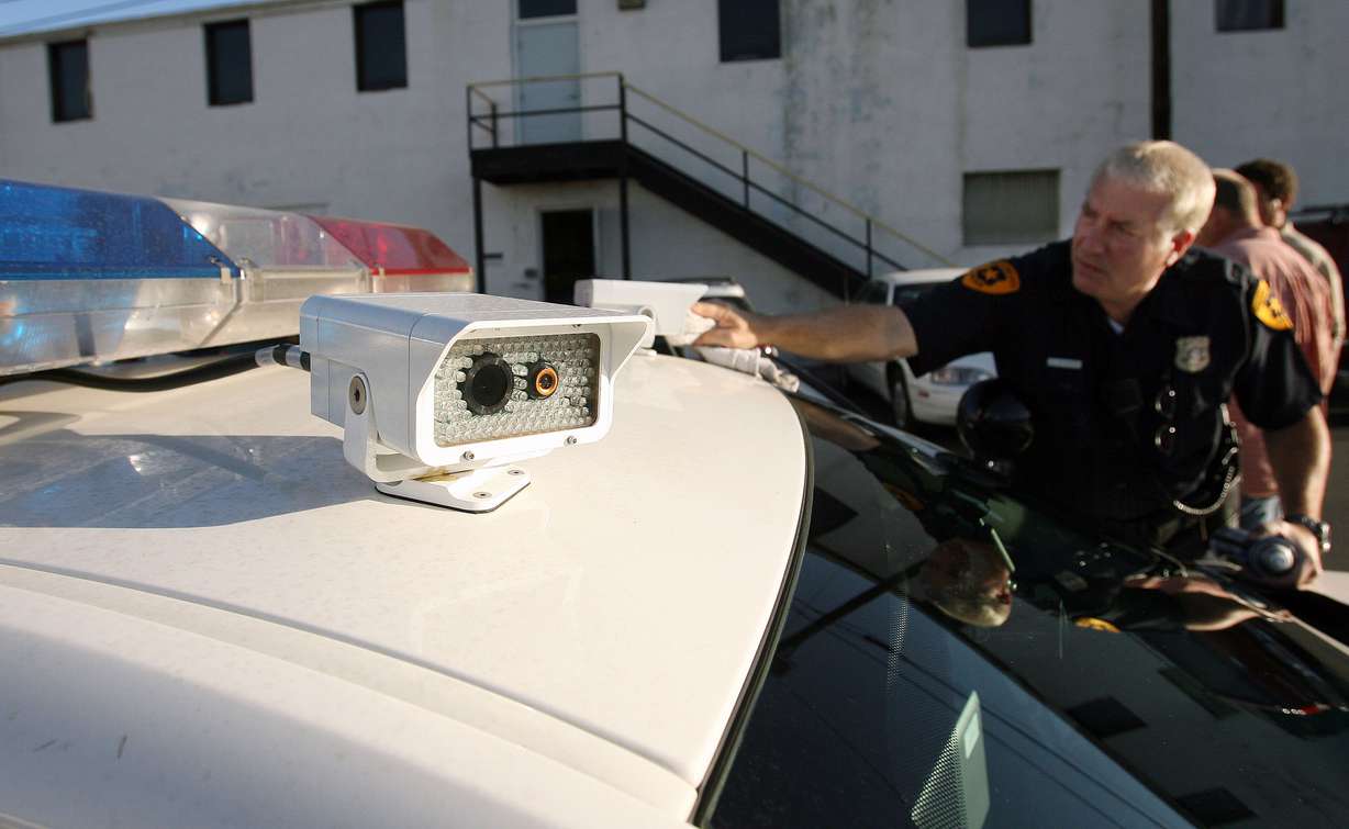 Salt Lake City police officer Al Hedenstrom cleans the lens for a license plate reader on a patrol car on Aug 8, 2007. The device instantly reports stolen cars, expired registration, etc. to the officers.