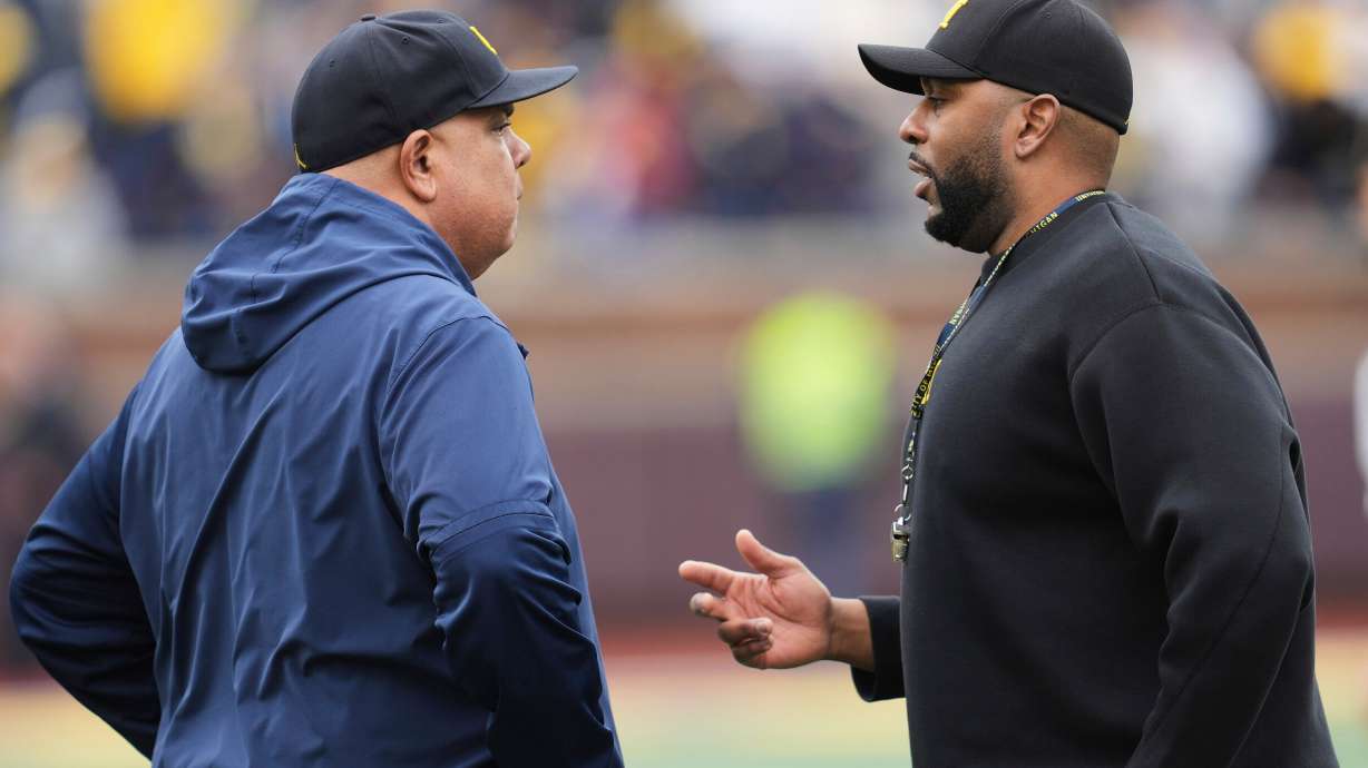 FILE - Michigan athletic director Warde Manuel, left, talks with head coach Sherrone Moore, right, before an NCAA college football spring game in Ann Arbor, Mich., April 19, 2025.