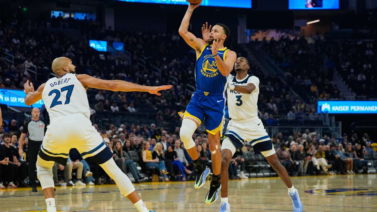 Golden State Warriors guard Stephen Curry (30) shoots between Minnesota Timberwolves center Rudy Gobert (27) and forward Jaden McDaniels (3) during the first half of an NBA basketball game, Friday, Dec. 12, 2025, in San Francisco.