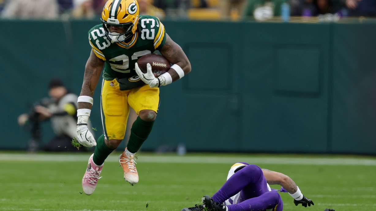 Green Bay Packers running back Emanuel Wilson (23) runs with the football after avoiding a tackle by Minnesota Vikings cornerback Byron Murphy (7), right, during the second half of an NFL football game Sunday, Nov. 23, 2025, in Green Bay, Wis.