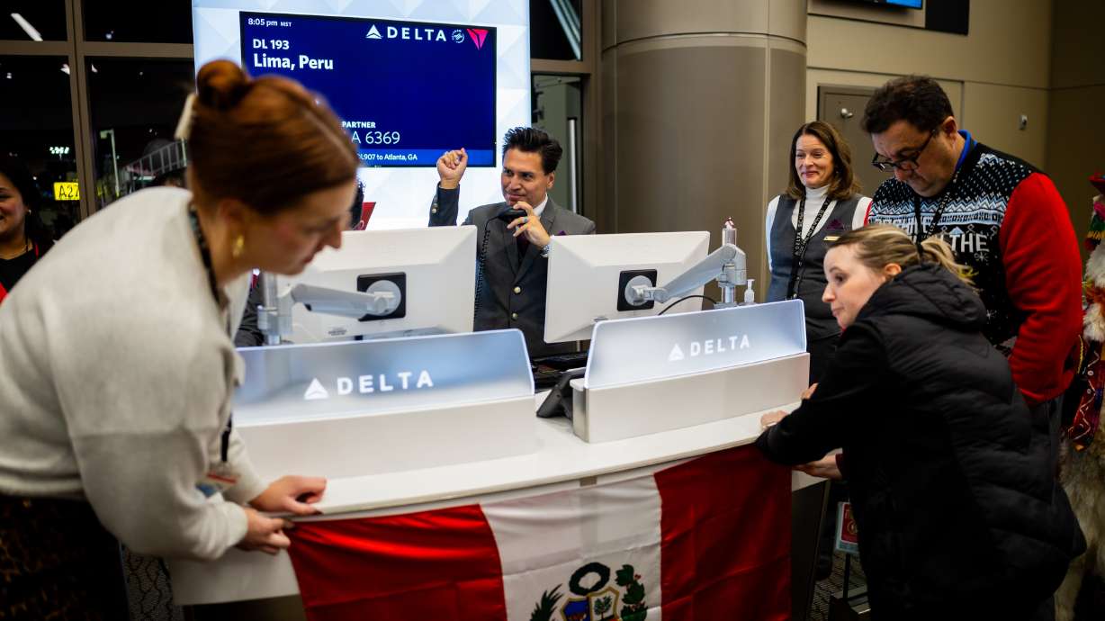 Victor Avalos, center, works as customer service agent as people pin up the flag of Peru for Delta’s maiden flight from Salt Lake City to Lima, Peru, at the Salt Lake City International Airport on Dec. 4.