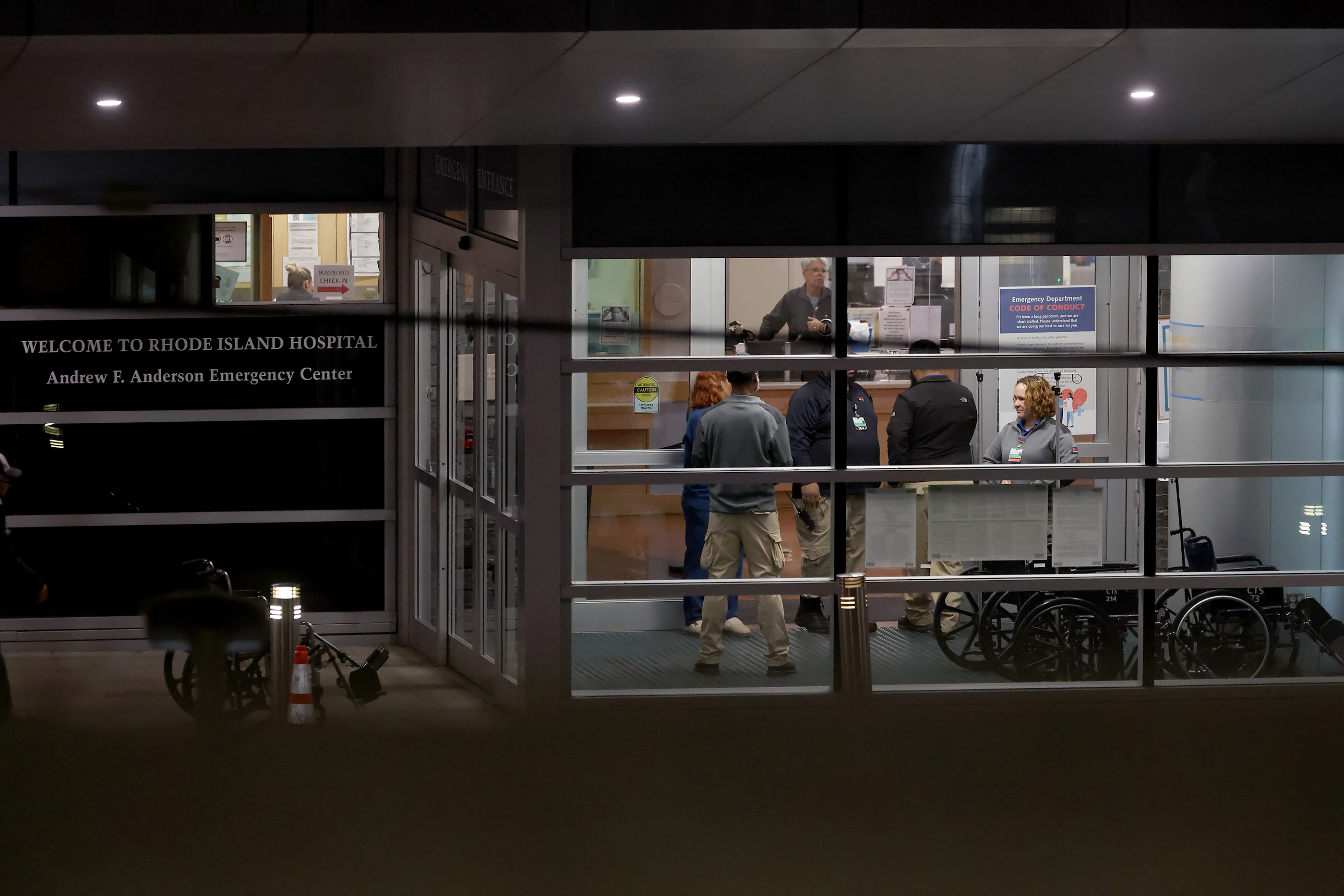 People stand at an entrance to Rhode Island Hospital in Providence, R.I., on Saturday, where victims from a shooting at Brown University were transported. Six of the victims were in critical, but stable condition.